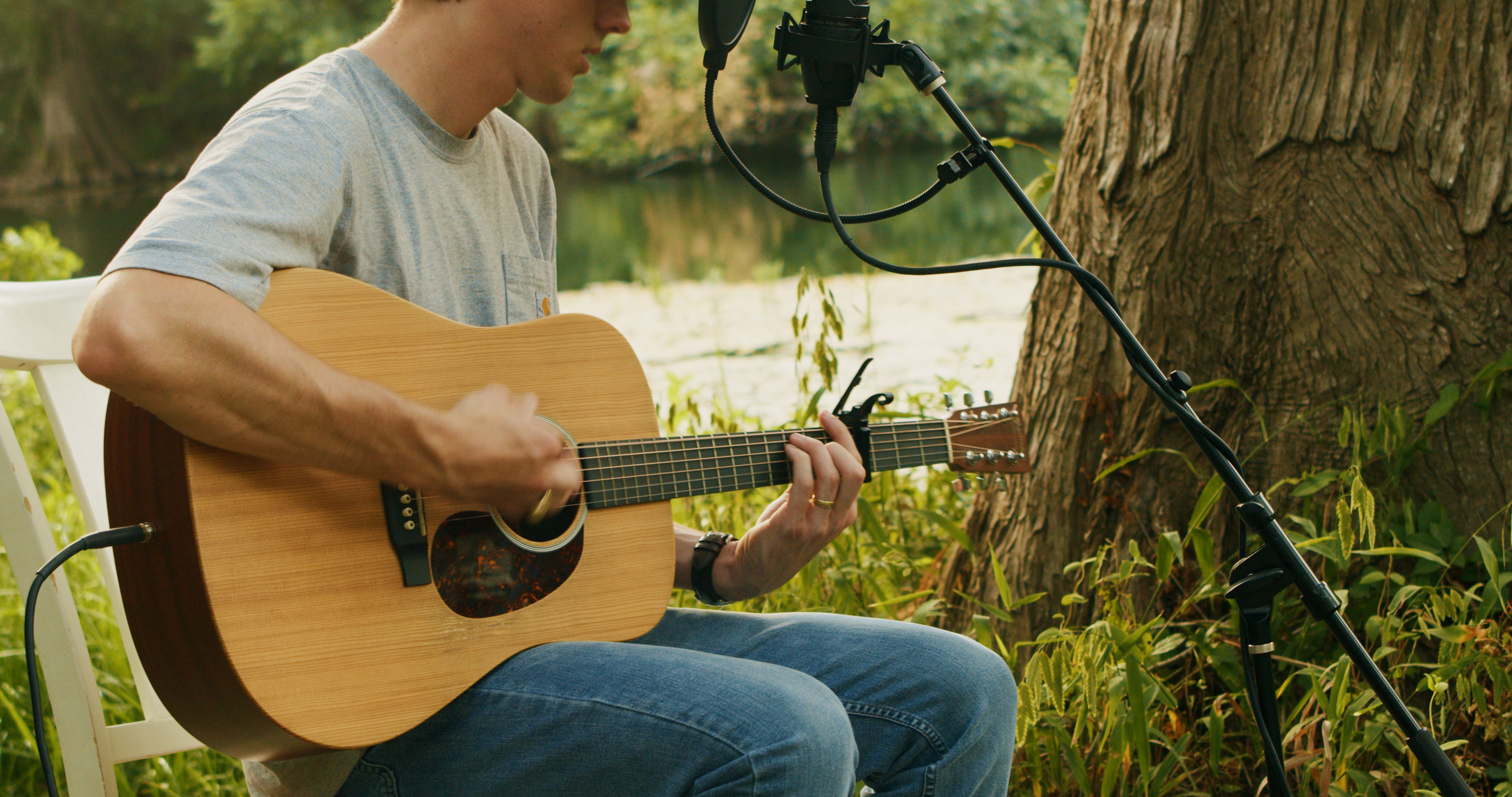 Close-up of Dylan Gossett playing guitar by the river